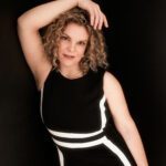 Curly brown haired Maya in elegant black dress.