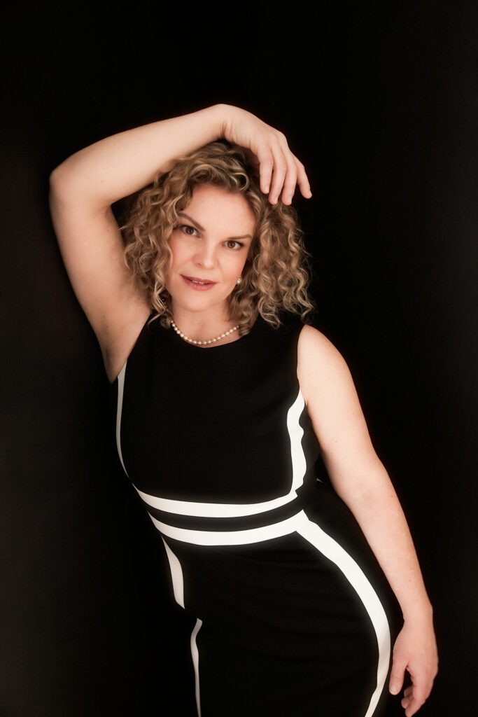 Curly brown haired Maya in elegant black dress.