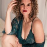 Wearing a green lingerie-like dress that exposes one shoulder.
