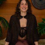 Khyla with a warm smile, sitting on a soft sheepskin.