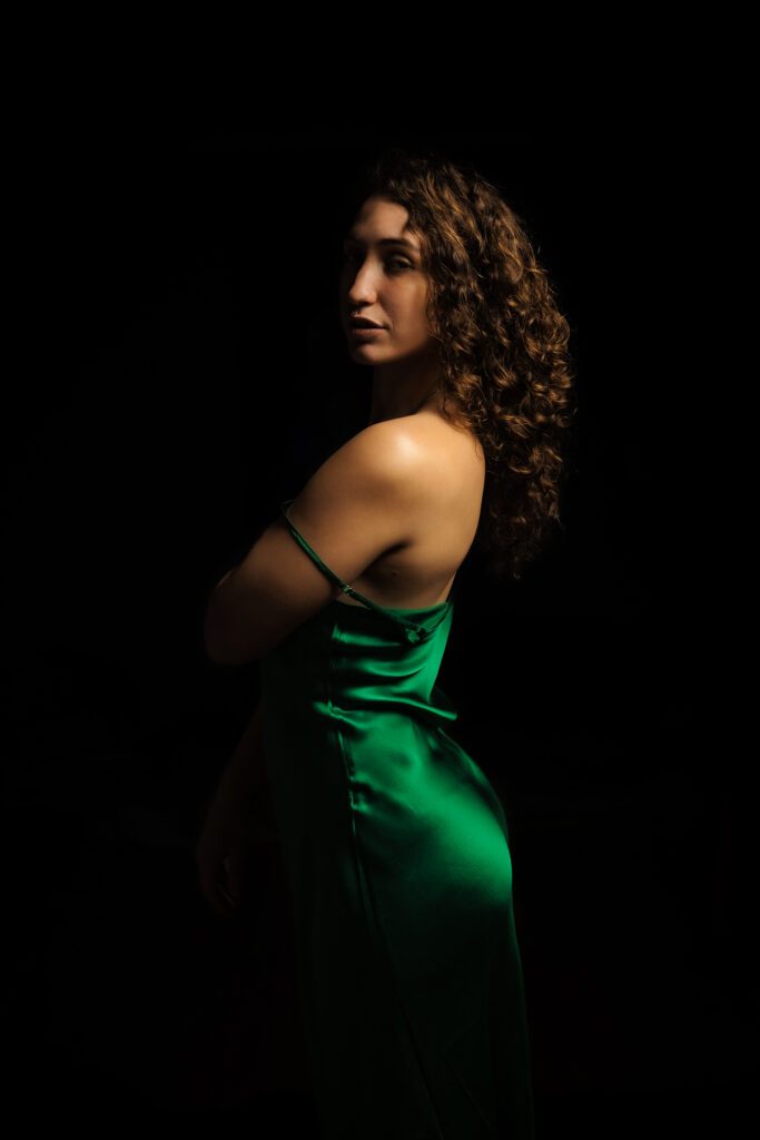 Dark background. Khyla in the front in a green velvet dress.