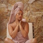 Opal Wolfe sitting on a bed wrapped in a towel.