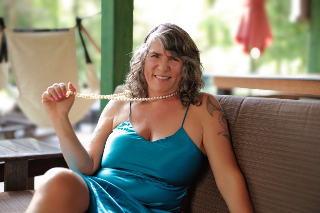 Justine with a big smile pulling on her necklace.