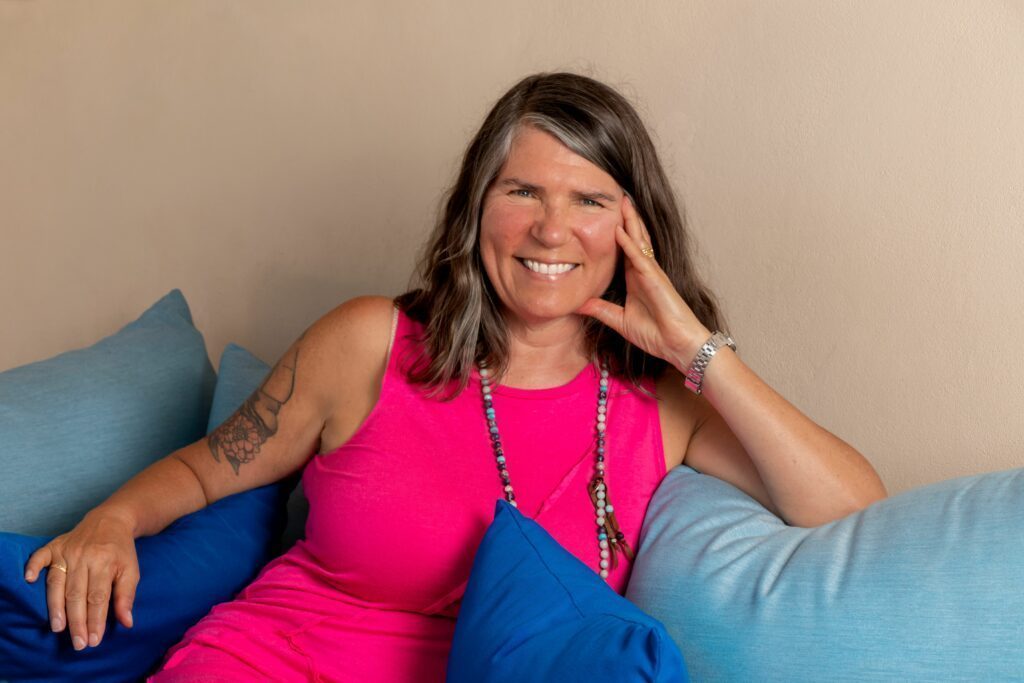Justine smiling on the sofa in a pink top
