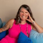 Justine smiling on the sofa in a pink top