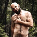 Naked upper half of michael in the woods, One arm covering the chest.