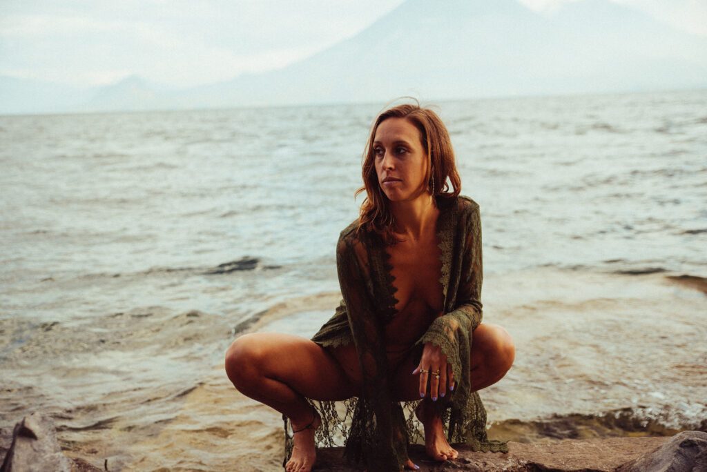 Joy Shakti squatting on the beach.