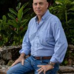Phil in blue shirt and blue jeans with a warm smile.