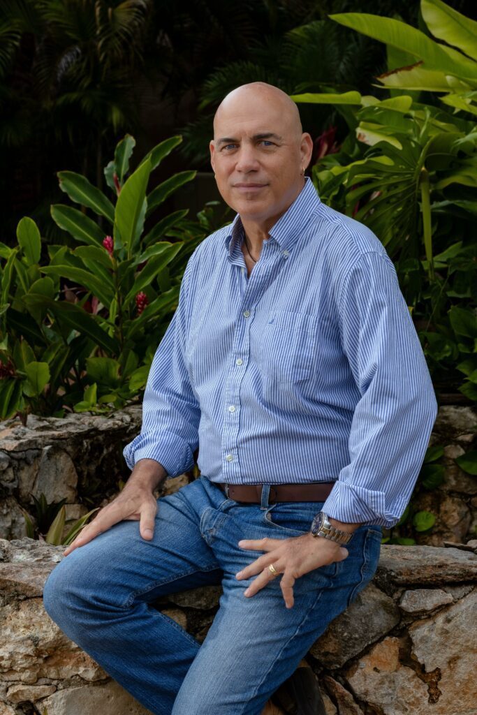 Phil in blue shirt and blue jeans with a warm smile.
