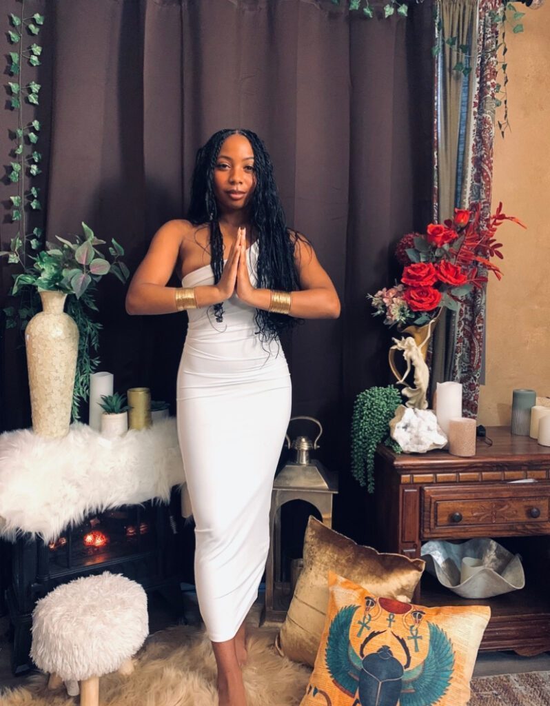 Welcome-stance with her hands together in prayer in front of the chest.