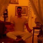 Nicholas sitting cross legged by a row of candles.