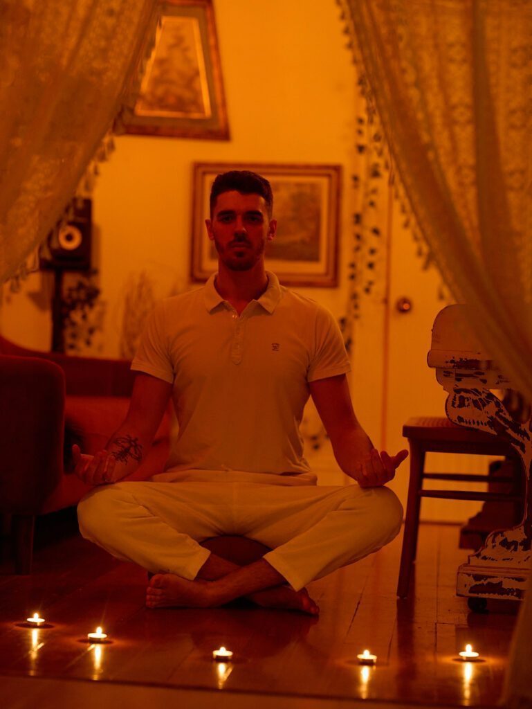 Nicholas sitting cross legged by a row of candles.