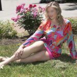 Cassy in a colorful pink dress sitting on grass.