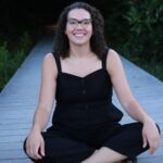 Liz Chandler sitting cross-legged on a wooden terrace.