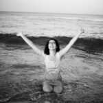 Kneeling in the sea with arms lifted towards the sky.