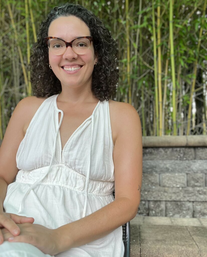 Sitting on a bench. Liz has a big friendly smile.