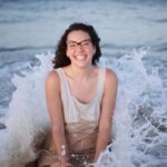 Liz in the waves in her dress that is getting wet.
