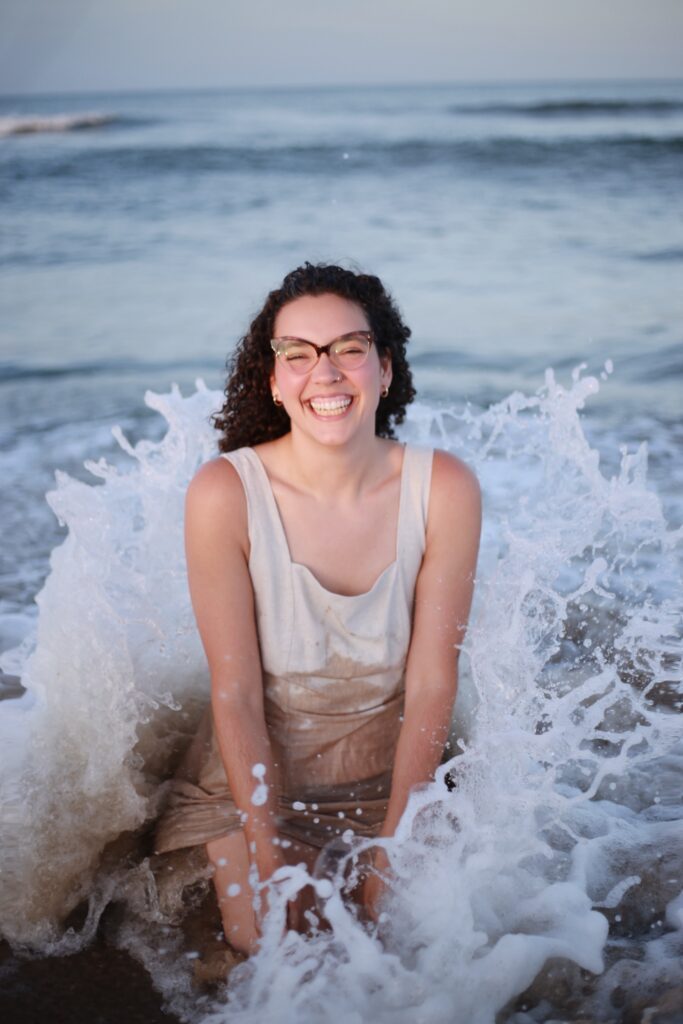 Liz in the waves in her dress that is getting wet.