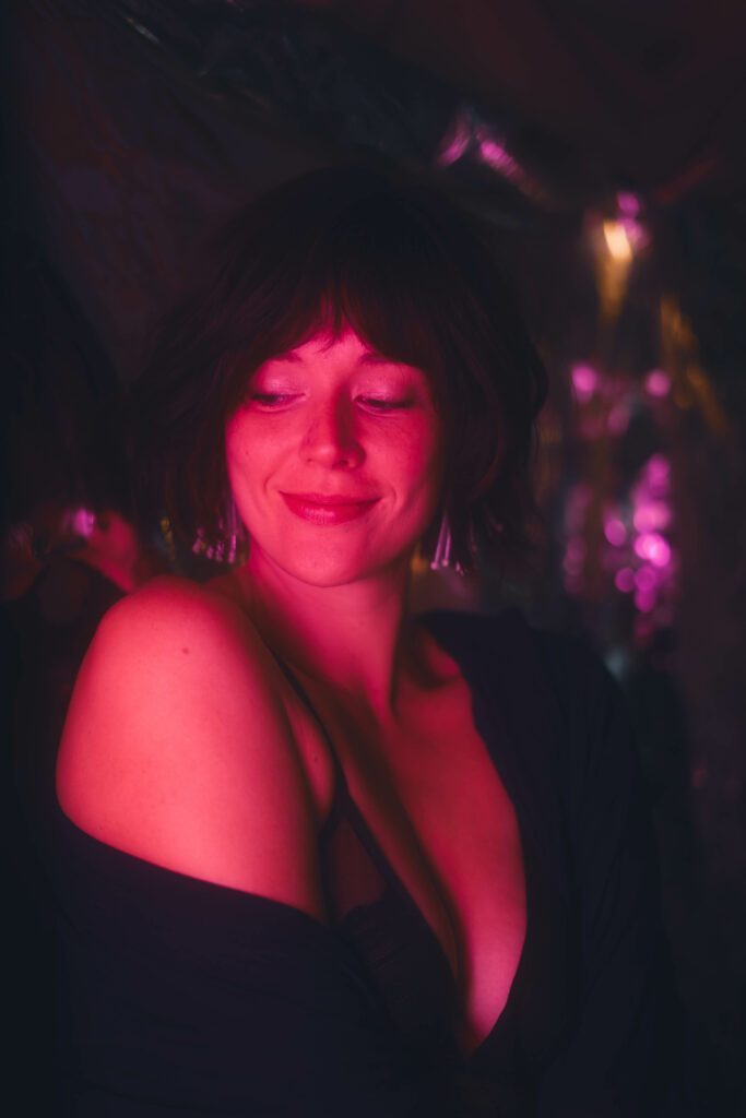 Warm smile, red light, dark room.