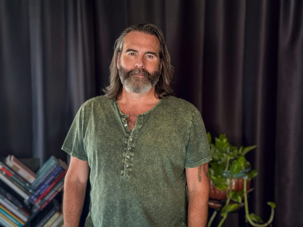 Dennis standing in a neutral position in green shirt.