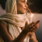 Amara wrapped in a white foulard holding a candle.