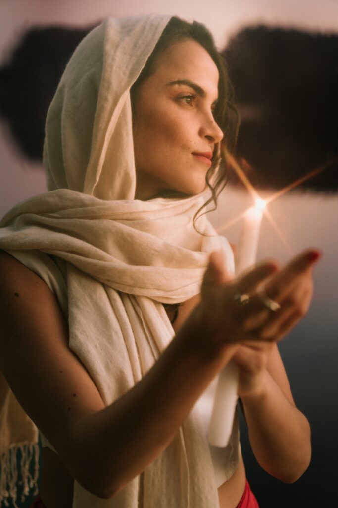 Amara wrapped in a white foulard holding a candle.