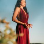 Amara in a long red dress taking a deeo breath in.