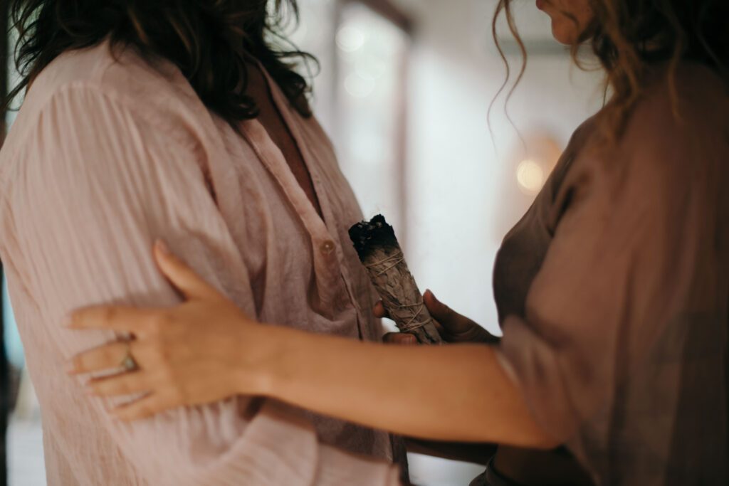 Aphrodisia holding a sage stick standing in front of a client.