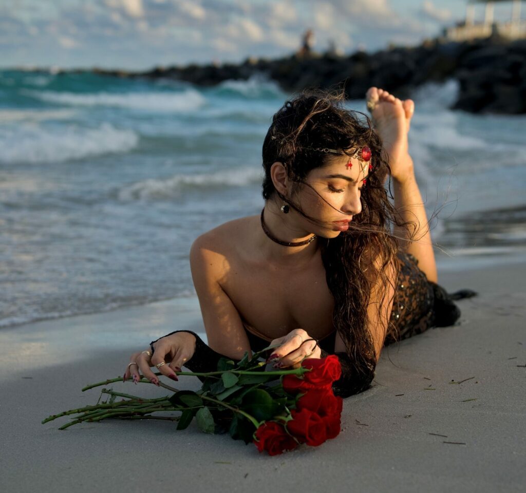 Sandy beach with selene lying on the sand with some roses.