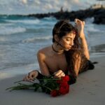 Sandy beach with selene lying on the sand with some roses.
