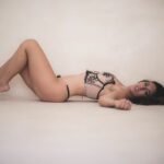 Aphrodisia on her back in sexy lingerie.