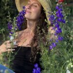 Rai in a straw hat smelling wild flowers.