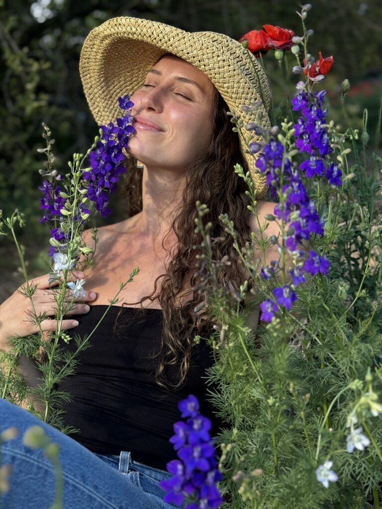 Rai in a straw hat smelling wild flowers.