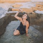 Keren in a natural pool pouring water on herself from a seashell.