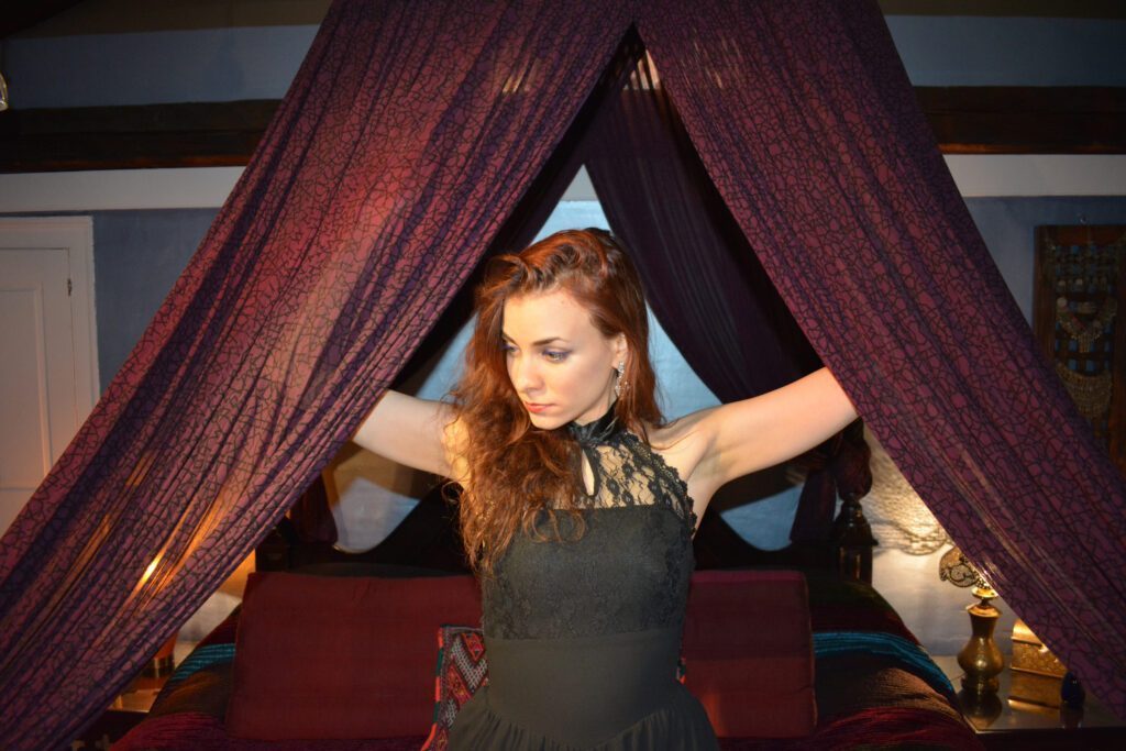 Viola opening the curtains to a bed.