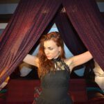 Viola opening the curtains to a bed.