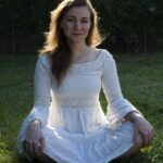 Viola in a pretty white dress sitting on the grass.