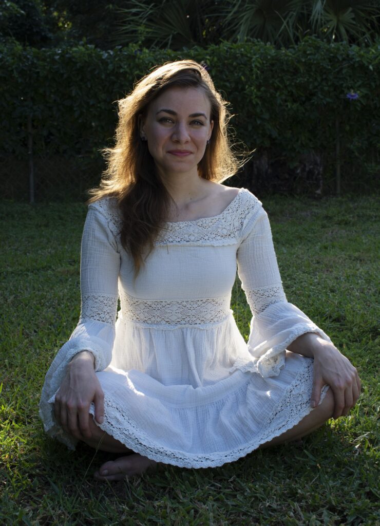 Viola in a pretty white dress sitting on the grass.