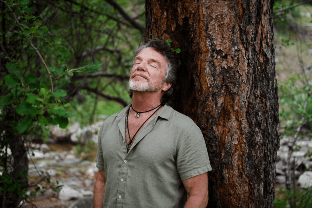 Rich leaning against a big tree with eyes closed.