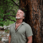Rich leaning against a big tree with eyes closed.