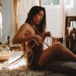 Tying a rope around her thighs, wearing a beige bodysuit.