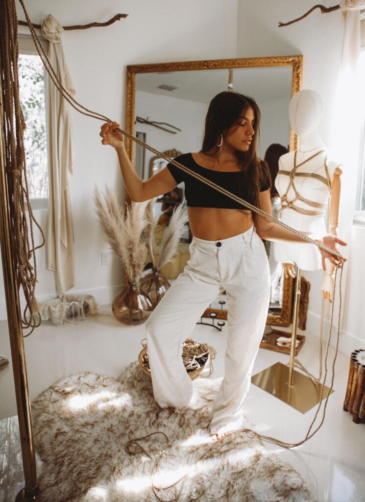 Jaqueline standing in her studio while holding a rope in her hands.