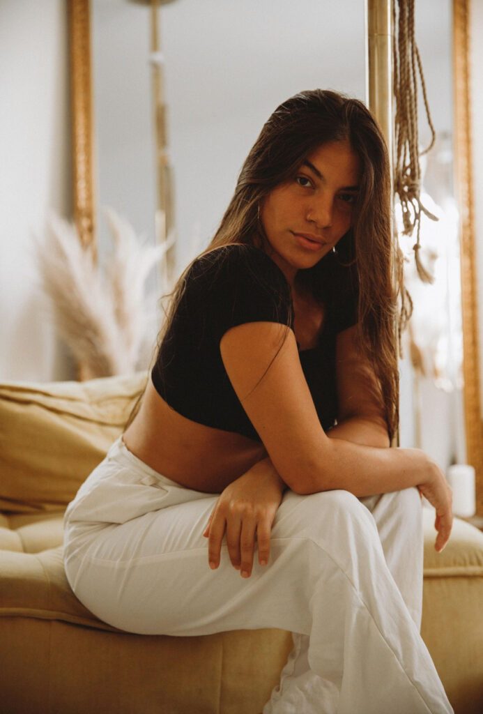 Sensual Shibari Artist sitting on the bed looking a the camera with a serious professional expression.