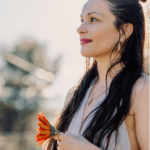 Eleanore holding a flower and looking to the distance