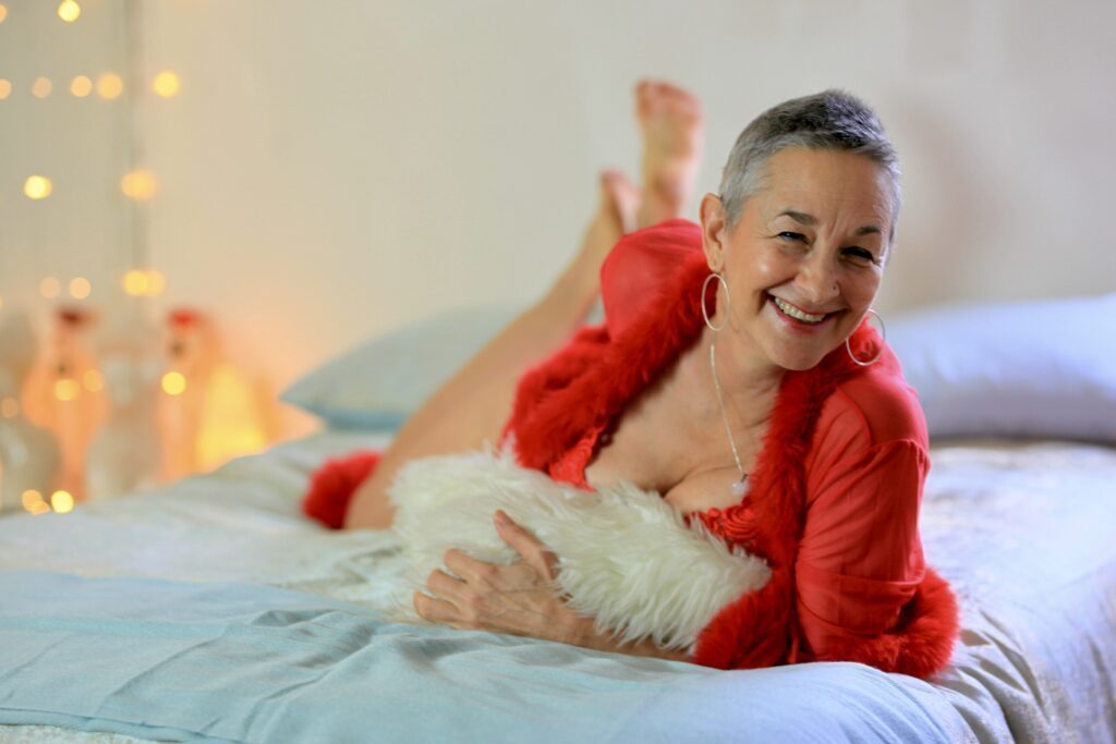 Luminara Joy on a bed in a red fluffy coat smiling to the camera.