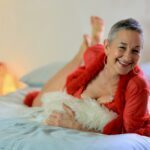 Luminara Joy on a bed in a red fluffy coat smiling to the camera.
