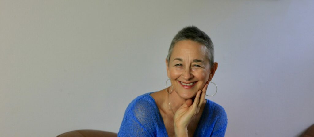 Sitting on an armchair, Luminara has a warm and inviting smile.