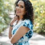 Triambika in a long blue dress and inviting smile.