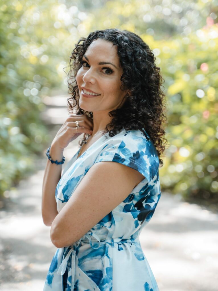 Triambika in a long blue dress and inviting smile.