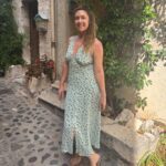 Juliette in a long airy dress by an old stone house.